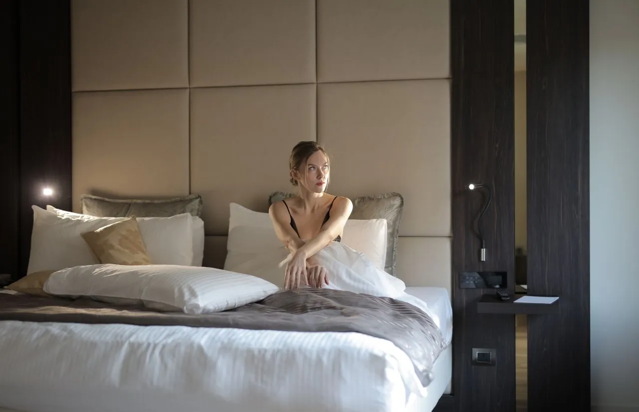 Elegant hotellrum med en välbäddad säng i vita och neutrala toner.